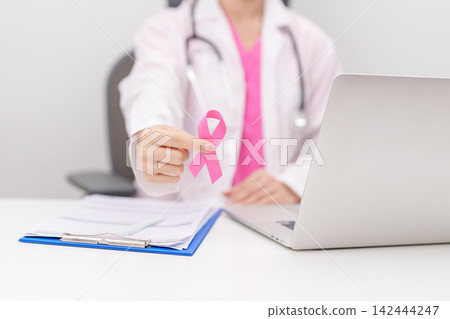 Doctor wearing lab coat giving pink ribbon to patient for Breast Cancer Awareness month, World Cancer Day, National Cancer Survivors Month, Pink October and Women Health empathy concept in hospital Doctor wearing lab coat giving pink ribbon to patient for Breast Cancer Awareness month, World Cancer Day, National Cancer Survivors Month, Pink October and Women Health empathy concept in hospital 142444247