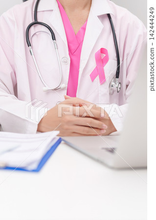 Professional doctor wearing lab coat using laptop and taking report notes on notebook for Breast Cancer Awareness month, World Cancer Day, National Cancer Survivors Month and Pink October in hospital Professional doctor wearing lab coat using laptop and taking report notes on notebook for Breast Cancer Awareness month, World Cancer Day, National Cancer Survivors Month and Pink October in hospital 142444249