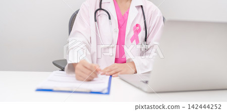 Professional doctor wearing lab coat using laptop and taking report notes on notebook for Breast Cancer Awareness month, World Cancer Day, National Cancer Survivors Month and Pink October in hospital Professional doctor wearing lab coat using laptop and taking report notes on notebook for Breast Cancer Awareness month, World Cancer Day, National Cancer Survivors Month and Pink October in hospital 142444252