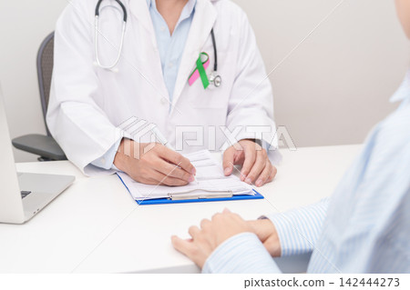 Doctor and patient having a medical consultation for green and pink ribbon to patient for concept of October Metastatic Breast Cancer Awareness month, National Cancer Survivors Month and Pink October Doctor and patient having a medical consultation for green and pink ribbon to patient for concept of October Metastatic Breast Cancer Awareness month, National Cancer Survivors Month and Pink October 142444273