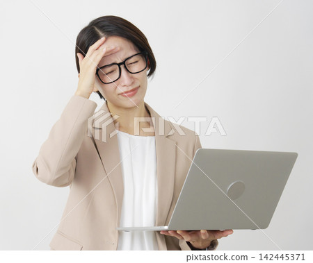 A middle-aged businesswoman struggling with her laptop against a white background. A middle-aged businesswoman struggling with her laptop against a white background. 142445371