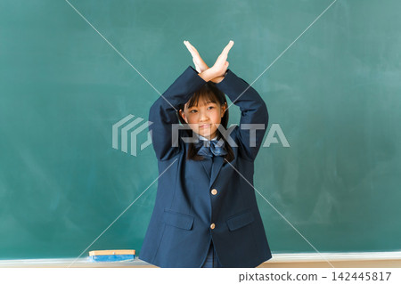 Junior high school and high school girls in uniform making a cross sign in front of the classroom blackboard Junior high school and high school girls in uniform making a cross sign in front of the classroom blackboard 142445817
