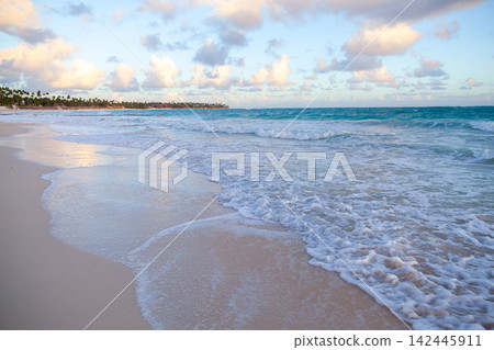 A tranquil tropical beach with gentle turquoise waves washing a wide sandy shore A tranquil tropical beach with gentle turquoise waves washing a wide sandy shore 142445911