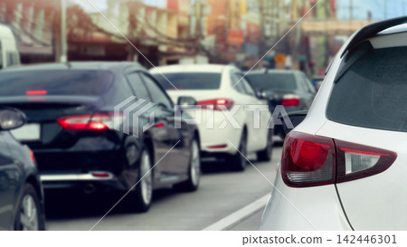 Vehicles are caught in heavy traffic congestion on a city road. During bright daytime hours with red tail lights visible. Vehicles are caught in heavy traffic congestion on a city road. During bright daytime hours with red tail lights visible. 142446301
