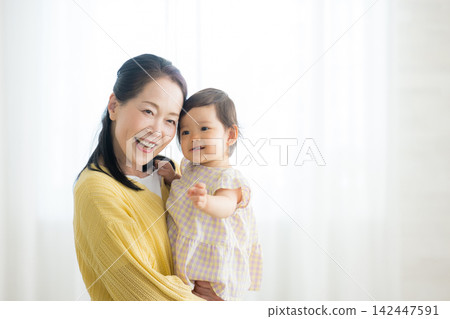 A grandmother holding her one-year-old daughter. A grandmother holding her one-year-old daughter. 142447591