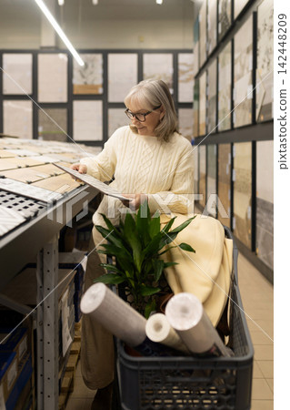 Senior woman shopping for tiles and home decor items for a house renovation project Senior woman shopping for tiles and home decor items for a house renovation project 142448209