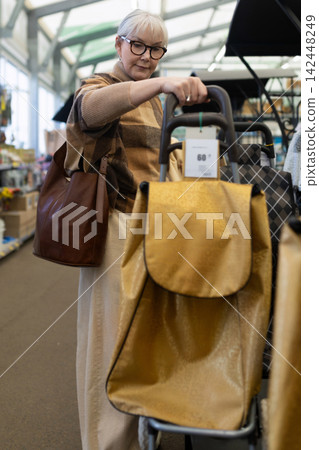 Senior woman considering a shopping trolley bag in a retail store Senior woman considering a shopping trolley bag in a retail store 142448249