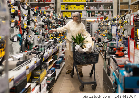 Woman selecting power tools from a shelf in a home improvement store aisle Woman selecting power tools from a shelf in a home improvement store aisle 142448367