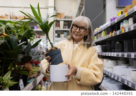 Senior woman selecting a new plant and matching decorative pot at a garden center Senior woman selecting a new plant and matching decorative pot at a garden center 142448391