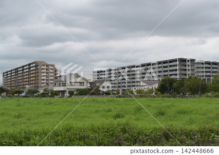 A rural apartment complex seen from a field on a summer afternoon. A rural apartment complex seen from a field on a summer afternoon. 142448666