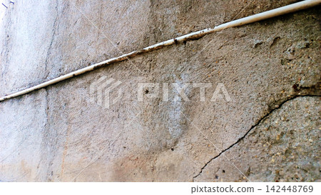 Textured concrete wall with pipes and cracks. 142448769