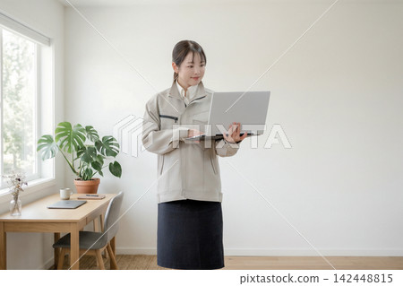 A woman checking her laptop while standing. A woman checking her laptop while standing. 142448815