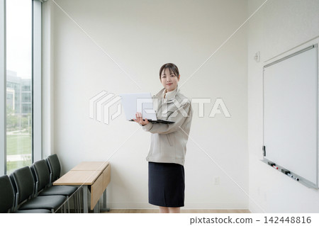 A woman stands in the conference room with her laptop. A woman stands in the conference room with her laptop. 142448816