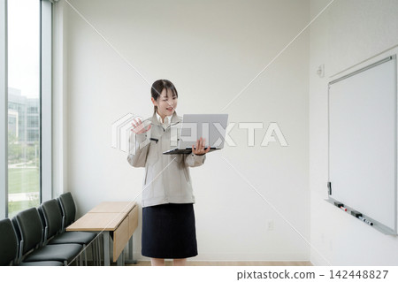 一位女士在會議室裡揮手,手裡拿著一台筆記型電腦。 一位女士在會議室裡揮手,手裡拿著一台筆記型電腦。 142448827