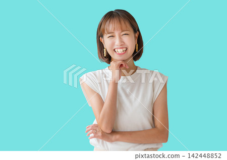 一位女子手托下巴,在碧藍色的背景下開懷大笑。 一位女子手托下巴,在碧藍色的背景下開懷大笑。 142448852