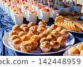 Cupcakes, cookies and fruit salad cups on a picnic table outdoors 142448959