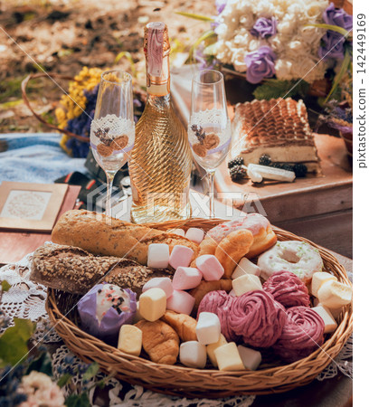 Closeup of picnic basket with drinks, food and flowers Closeup of picnic basket with drinks, food and flowers 142449169