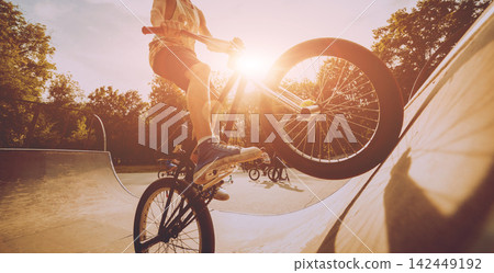 Boy riding a bmx in a park. 142449192