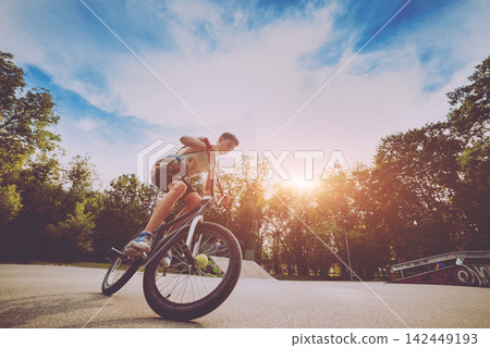 Boy riding a bmx in a park. 142449193
