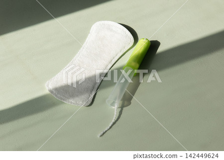 A sanitary napkin and a tampon lay in an even layer . The concept of choosing the most suitable means for feminine hygiene. A sanitary napkin and a tampon lay in an even layer . The concept of choosing the most suitable means for feminine hygiene. 142449624