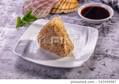 Triangle onigiri rice ball on white plate with soy sauce and seashells 142449967