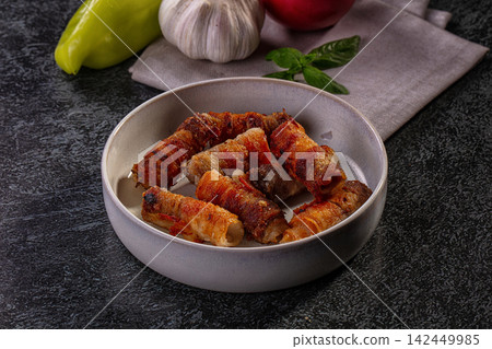 Crispy bacon wrapped meat rolls in ceramic bowl with garlic pepper and basil Crispy bacon wrapped meat rolls in ceramic bowl with garlic pepper and basil 142449985