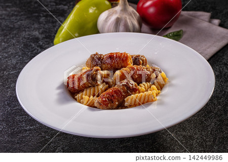 Pasta with bacon wrapped sausage on white plate Pasta with bacon wrapped sausage on white plate 142449986