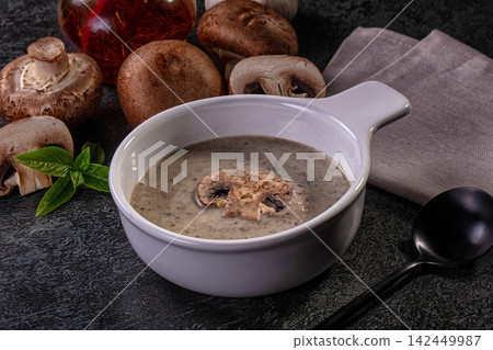 Creamy mushroom soup in white bowl with fresh mushrooms and basil on dark stone surface Creamy mushroom soup in white bowl with fresh mushrooms and basil on dark stone surface 142449987
