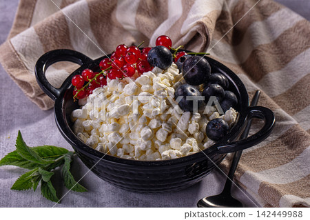 Cottage cheese bowl with blueberries and red currants on striped cloth Cottage cheese bowl with blueberries and red currants on striped cloth 142449988