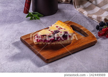 Slice of berry pie on wooden board with fresh blueberries and red currants 142449989