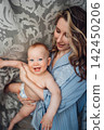 Laughing shirtless baby playing with mom near curtains 142450206