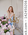 Redhead woman kneels among pink peonies and candelabra 142450208
