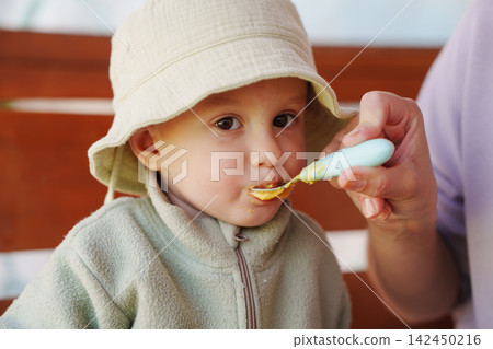 Cose-up of a Toddler Eating Baby Food from a Spoon Cose-up of a Toddler Eating Baby Food from a Spoon 142450216