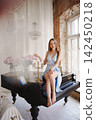 Elegant woman poses on grand piano indoors 142450218