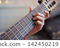 Learning to play chords on a guitar in a cozy setting 142450219
