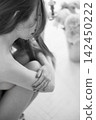 Nude woman embracing herself indoors, quiet moment 142450222