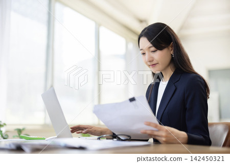 一位年輕的日本女商人正在明亮的窗邊使用筆記型電腦工作。 142450321
