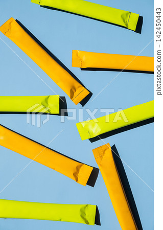 Yellow and green stick sachets on blue background. Yellow and green stick sachets on blue background. 142450443
