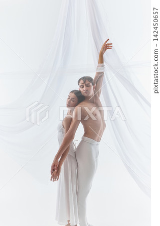 Close dance couple stretches upward in synchronized silhouette Close dance couple stretches upward in synchronized silhouette 142450657
