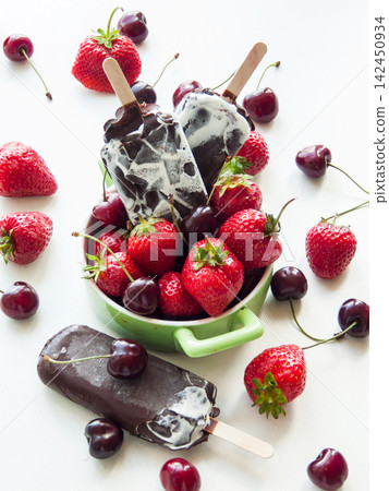 Sweet chocolate vanilla ice cream with red ripe strawberries and cherries, summer refreshing dessert Sweet chocolate vanilla ice cream with red ripe strawberries and cherries, summer refreshing dessert 142450934