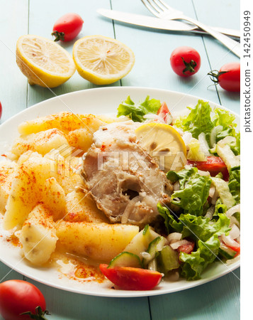 Juicy fried seafood pollock fish steaks with boiled potatoes and tomatoes lettuce onion salad Juicy fried seafood pollock fish steaks with boiled potatoes and tomatoes lettuce onion salad 142450949