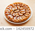 Traditional homemade French apple tarte tatin on white plate over wooden background 142450972