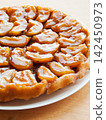 Traditional homemade French apple tarte tatin on white plate over wooden background 142450973