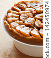 Traditional homemade French apple tarte tatin on white plate over wooden background 142450974