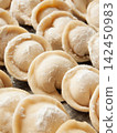 Raw homemade handmade russian pelmeni dumplings rows sprinkled with flour on metal tray 142450983