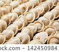 Raw homemade handmade russian pelmeni dumplings rows sprinkled with flour on metal tray 142450984