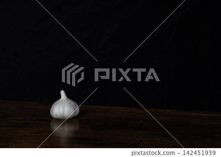 Garlic bulb on a dark wooden surface with a black background 142451939