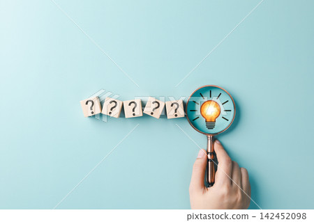 Problem Solving and Idea Discovery Concept. Hand holding magnifying glass over question mark blocks and light bulb representing creative thinking, solution search, innovation, answer finding, insight Problem Solving and Idea Discovery Concept. Hand holding magnifying glass over question mark blocks and light bulb representing creative thinking, solution search, innovation, answer finding, insight 142452098