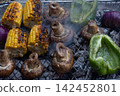 Fresh corn, mushrooms, bell pepper and red onion cooking on a smoky barbecue grill 142452801