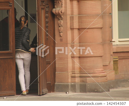 Woman entering in a building Woman entering in a building 142454307